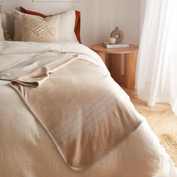 Jeté beige en laine de mérinos sur lit / Merino wool throw on bed made in Canada by Volprivé.