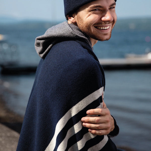 Couverture bleue marine laine de mérinos sur épaule jeune homme au lac / Navy blue with white stripes merino wool blanket on shoulders of young man with water background.