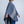 Vue de côté jeune femme portant châle en laine mérinos gris avec rayures beiges / Side view of young women wearing a grey with beige stripes merino wool shawl made in Canada by Volprivé.