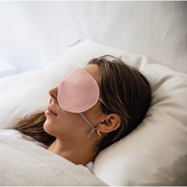 Jeune femme couchée sur un lit blanc avec masque de nuit rose / Young women asleep on white bed with night mask pink by Volprivé.