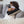 Jeune homme assis sur fauteuil avec oreiller de voyage et masque de sommeil noir / Young man lounging with neck pillow and mask in black merino wool by Volprivé..