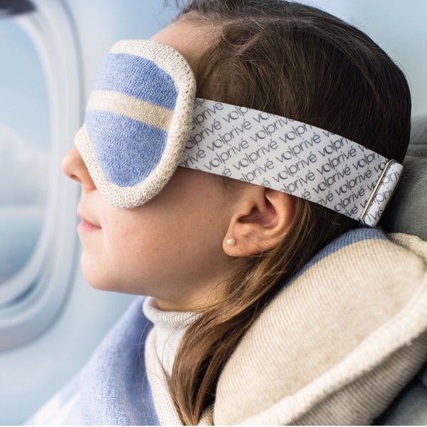 Jeune fille portant masque de sommeil lesté bleu pâle en avion siège hublot / Young girl wearing a pâle blue weighted sleep mask on plane window seat made by Volprivé.