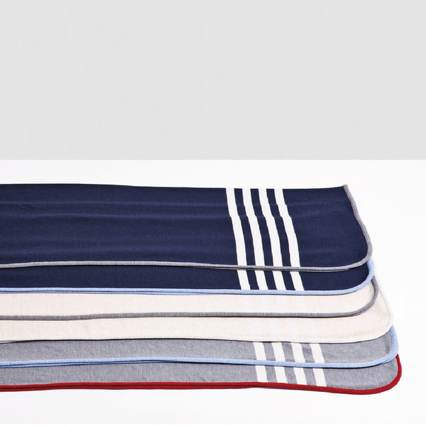 Assortiment à plat de couvertures en laine de mérinos avec rayures blanches / Merino wool blankets with white stripes made in Canada by Volprivé.