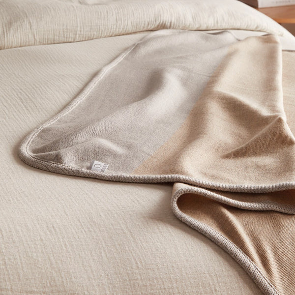 Gros plan jeté beige en laine de mérinos sur lit / Close up of a beige merino wool throw on bed made in Canada by Volprivé.