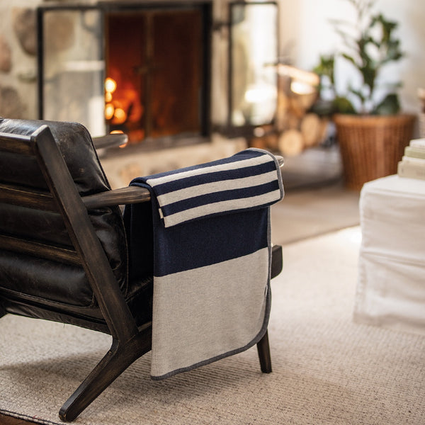 Jeté bleu marine avec rayures blanches en laine de mérinos devant foyer / Navy with white stripes merino wool throw in front of fire place made in Canada by Volprivé.