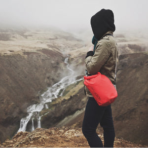 Jeune femme avec capuchon fjord Islandais et Sac au sec 5L rouge de Volprivé / Young women in Iceland with a red 5L dry bag by Volprivé.