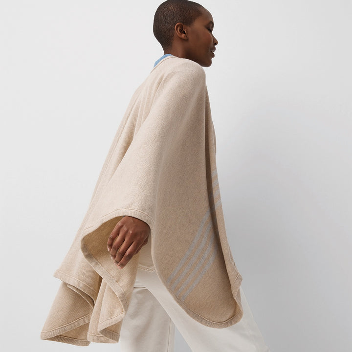 Vue de côté jeune femme portant châle en laine mérinos beige / Side view of young women wearing a beige merino wool shawl made in Canada by Volprivé.